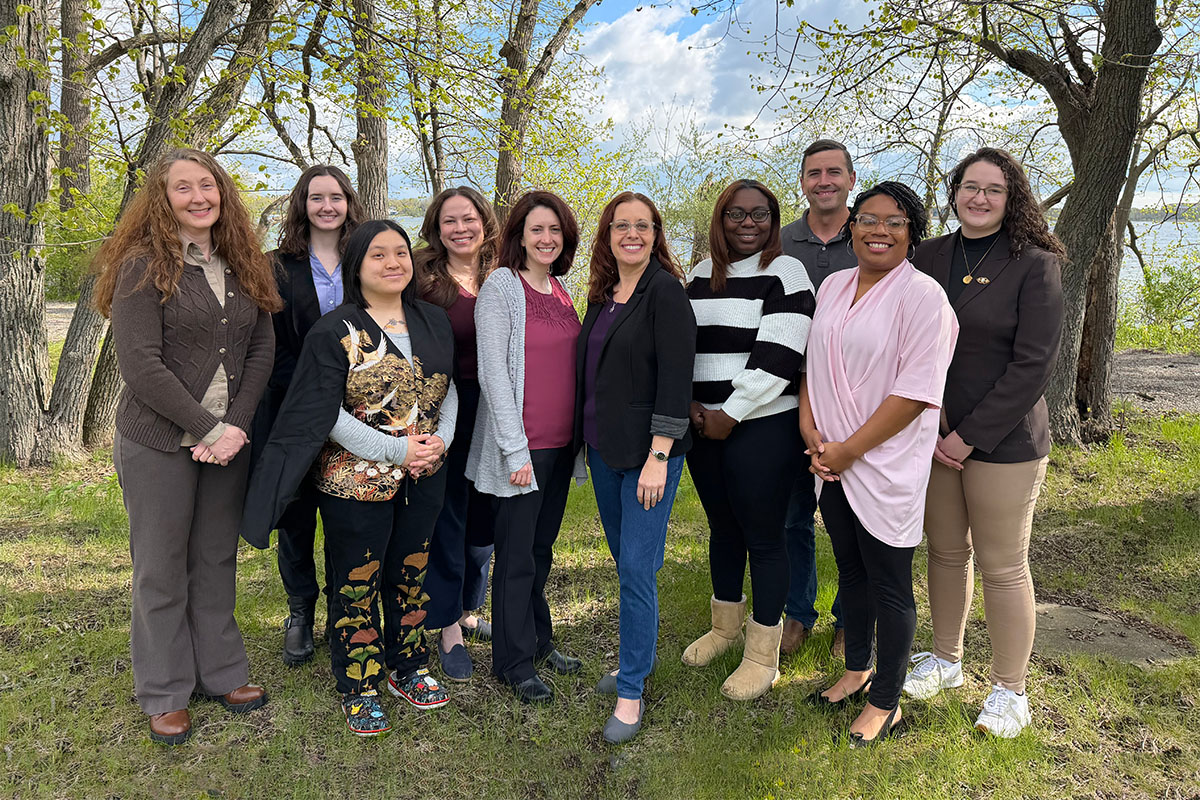 Bradley Counseling clinical team standing together outdoors near a wooded lakeside setting.